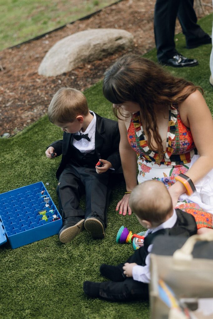 Children playing with toys outside during cocktail hour in documentary style wedding photos.
