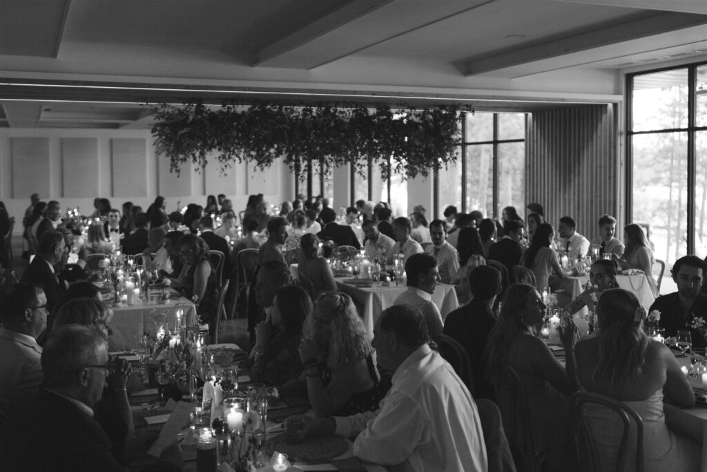 Black and white photo of guests dining and laughing during the Catalyst wedding reception.