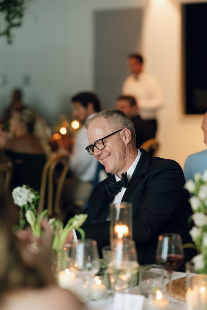 Bride’s father smiling during speeches.