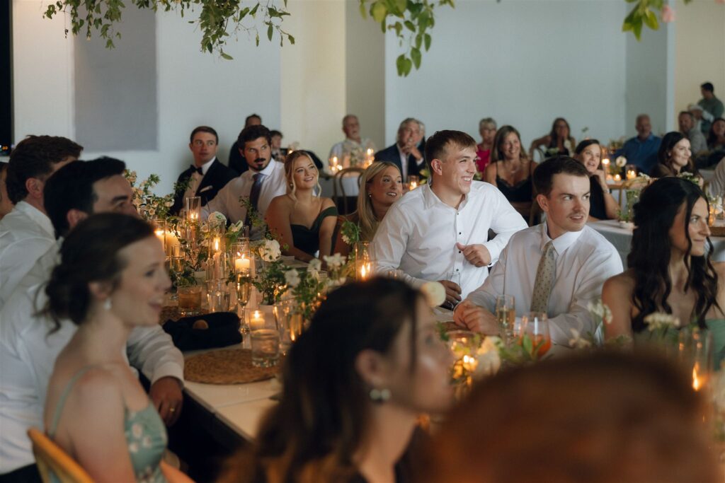 Guests laughing and reacting during wedding speeches in candid wedding photography.