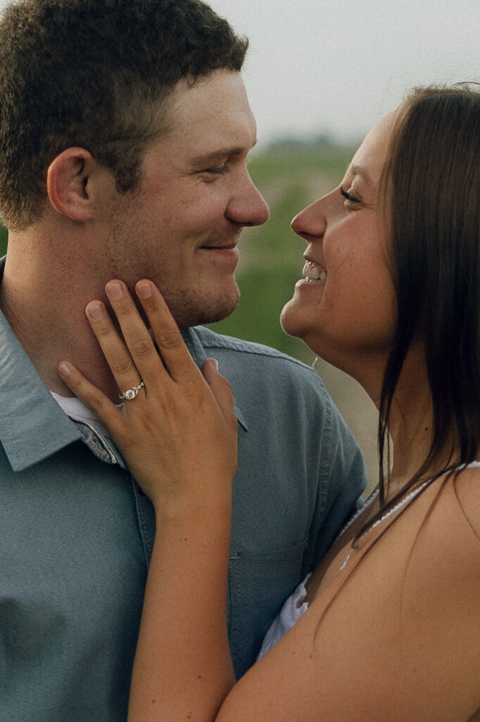 Sophie smiling up at Jake, showing off her engagement ring as they share a playful, love-soaked moment.