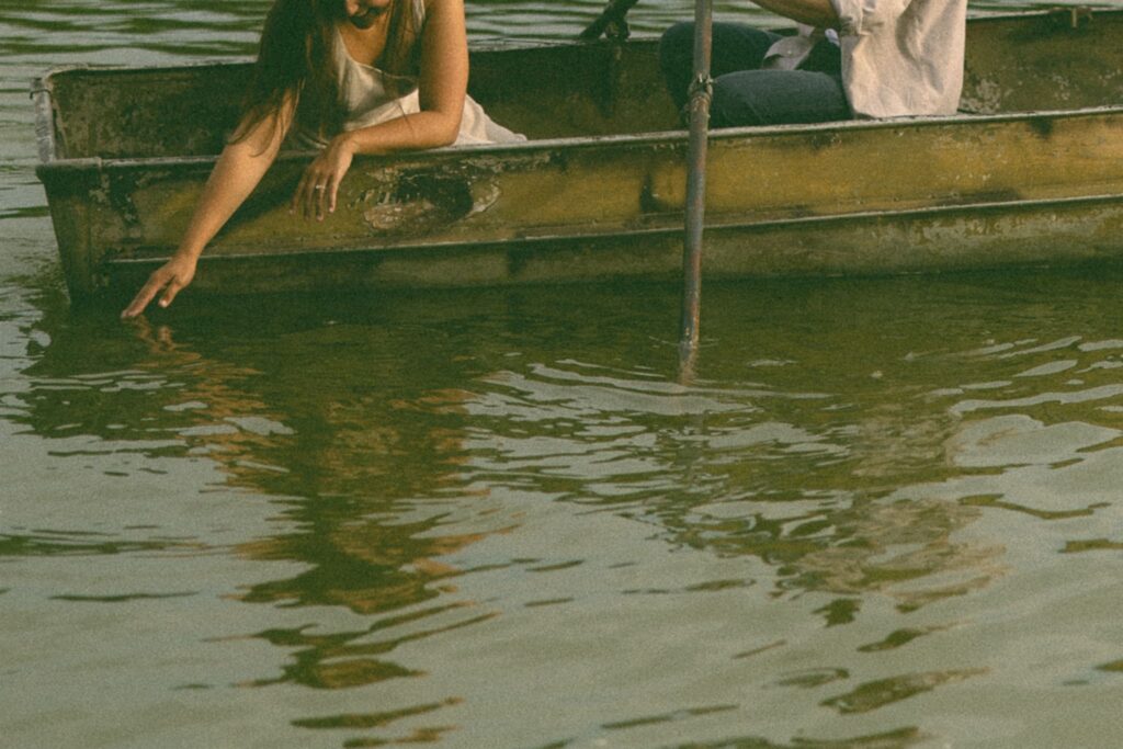 Sophie trails her fingers through the lake while the boat drifts lazily nearby, one of many nostalgic storytelling engagement photos that feels equal parts calm, tender, and beautifully unscripted.