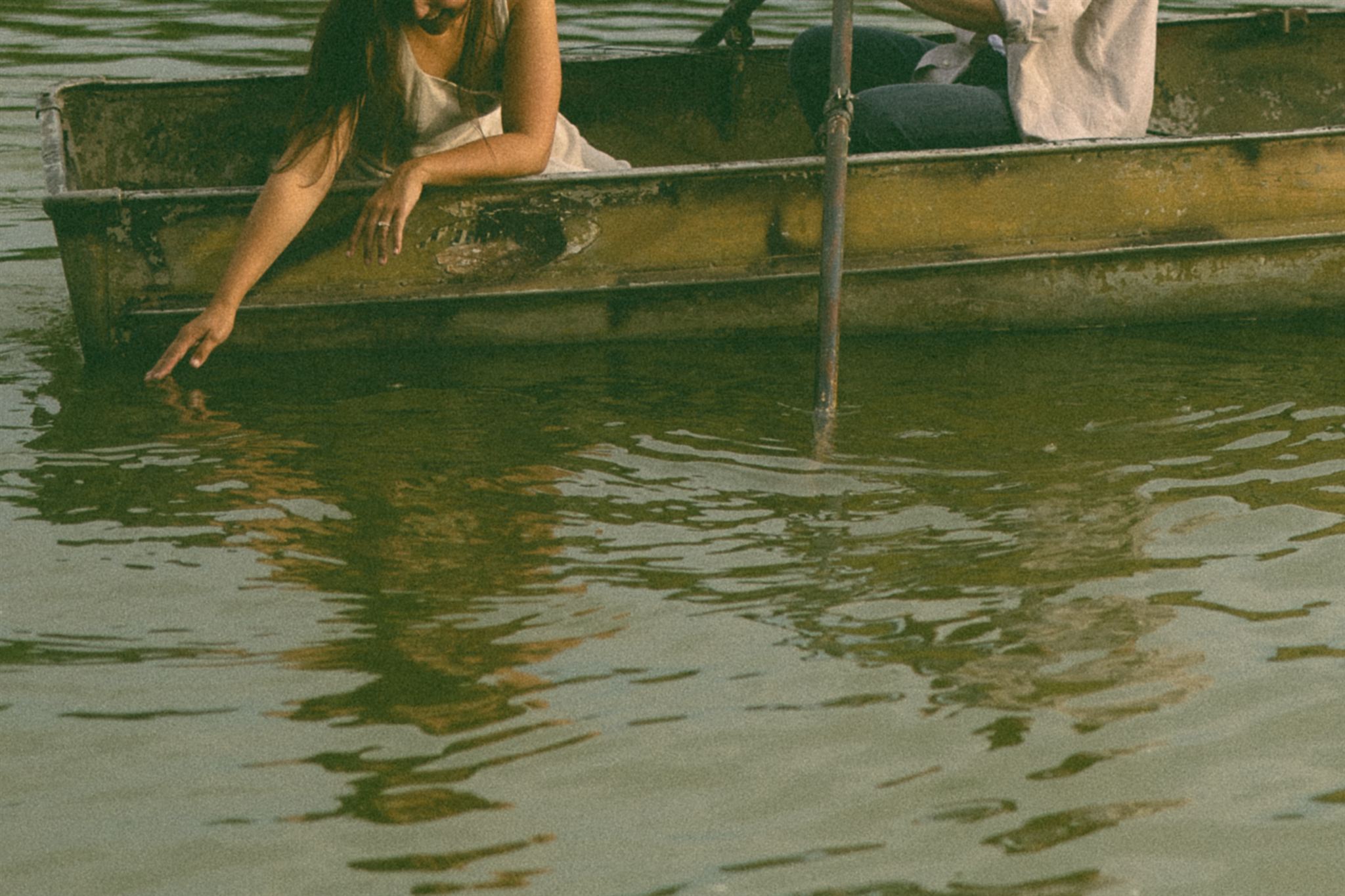 Sophie trails her fingers through the lake while the boat drifts lazily nearby, a nostalgic engagement photo that feels equal parts calm, tender, and beautifully unscripted.