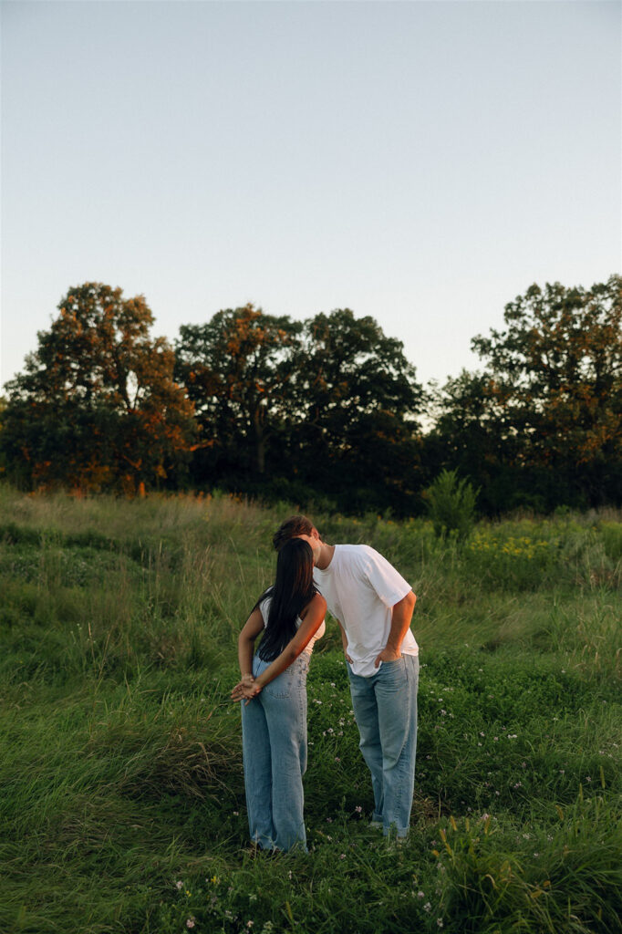 Jake and Amira standing in an open meadow, sharing a kiss as the sky opens up above them and the field surrounds them.