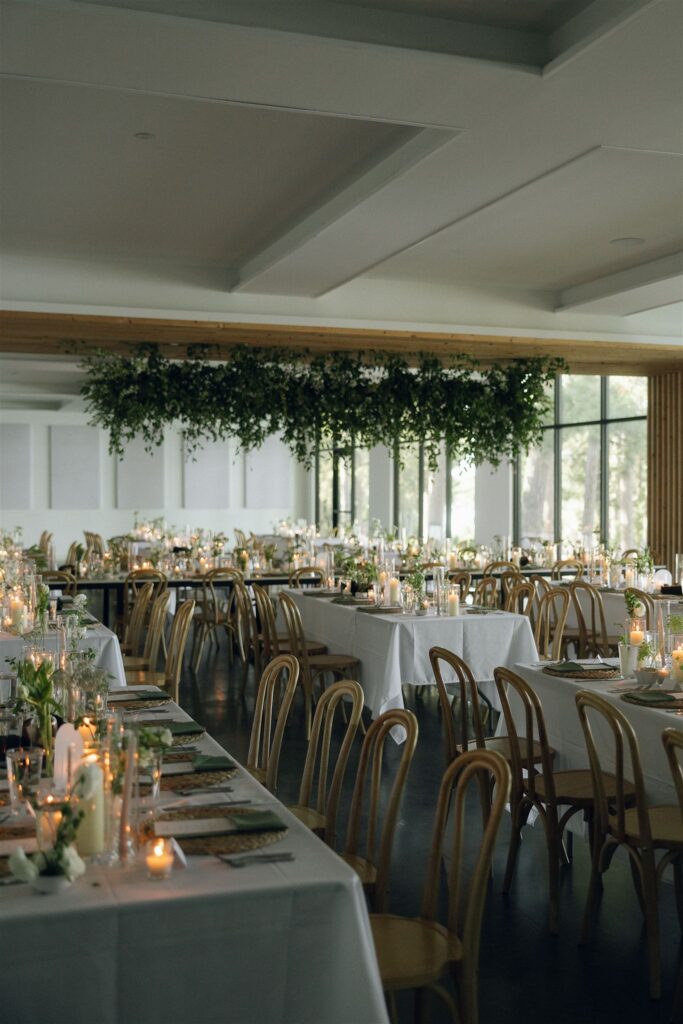 Reception space at Catalyst by Nature Link set with long tables, bentwood chairs, candles, and greenery installations, showcasing a modern indoor wedding setup at one of the best wedding venues in Minnesota.