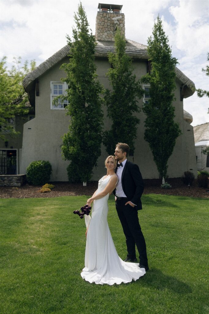 Bride and groom stand together on the lawn at Edward Anne Estate at Bavaria Downs, with the estate building and manicured grounds behind them.