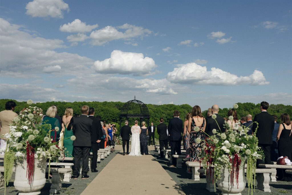 Outdoor wedding ceremony at Edward Anne Estate with guests seated along a central aisle leading to a garden gazebo, a classic layout among the best wedding venues in Minnesota.