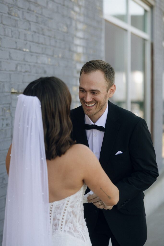 Groom smiles broadly as he sees the bride for the first time, standing outside Forgotten Star Brewing in Minnesota.
