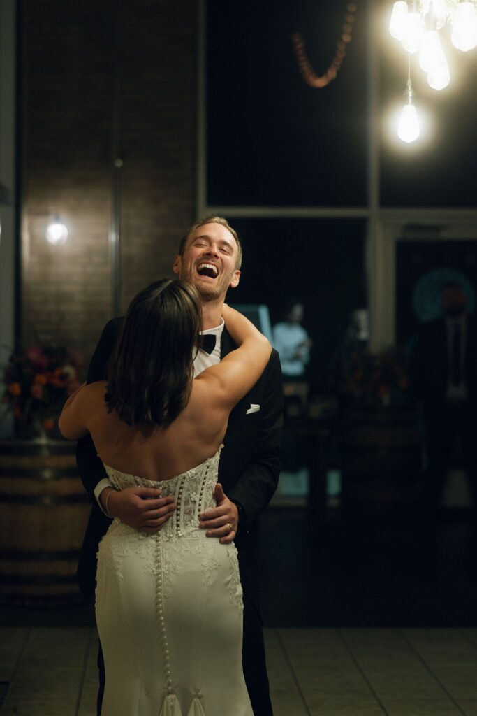 Bride and groom laughing and hugging during their Minnesota wedding reception, showcasing joyful candid moments and relaxed wedding planning resources in action.