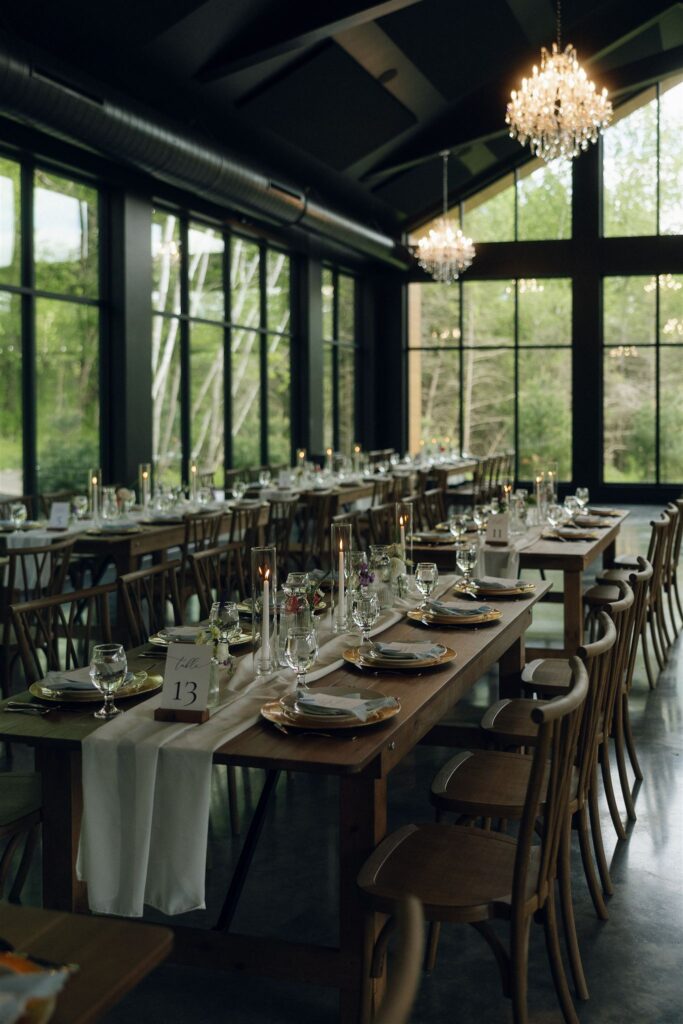 Elegant reception tables set inside Woods and Co Weddings and Events, showcasing one of the best Stillwater, Minnesota wedding venues with floor-to-ceiling windows, chandeliers, and a modern woodland atmosphere.