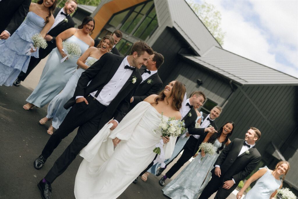 Wedding party walking together outside Woods and Co Weddings and Events, laughing mid-step in a relaxed group portrait at one of the best wedding venues in Minnesota.