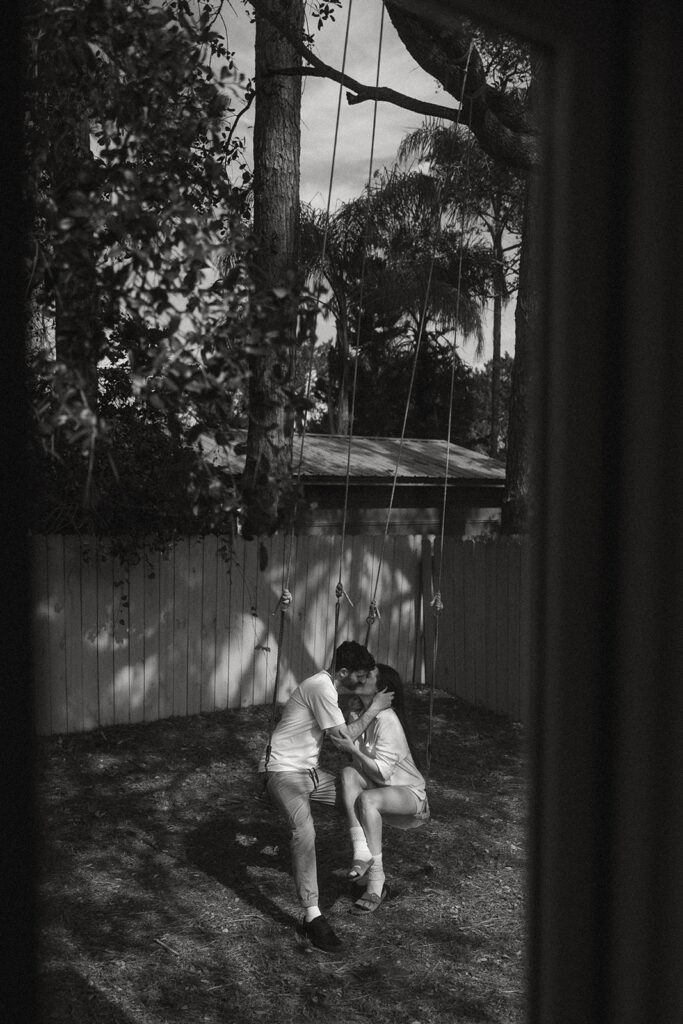 Black and white version of the same swing-side moment, soft shadows and stillness turning their backyard into something cinematic and intimate.