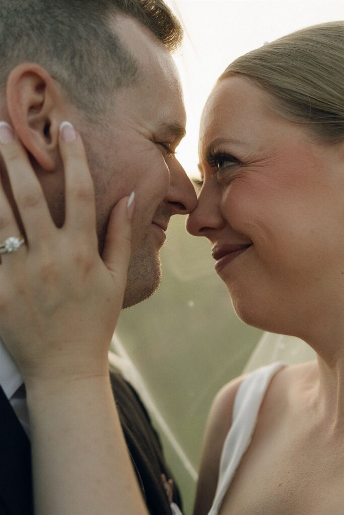 Close-up golden hour portrait of bride and groom smiling nose-to-nose in the vineyard at 7 Vines Vineyard and Winery.