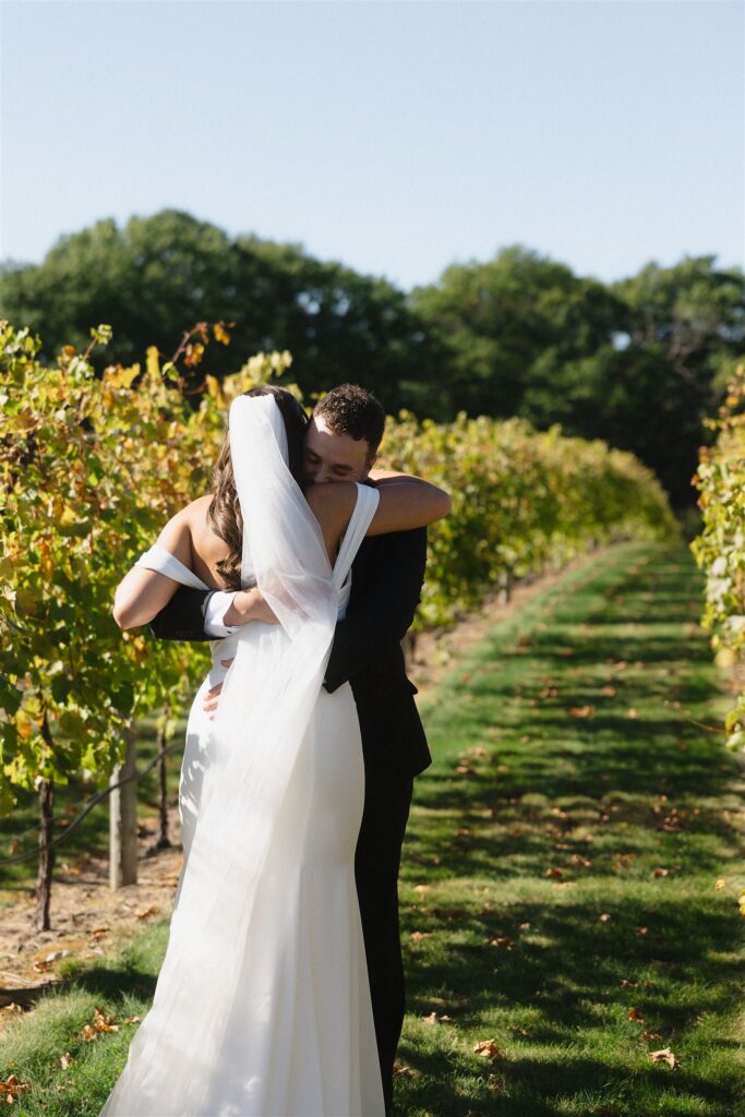 Bride and groom embracing between the vineyard rows during their fall wedding at 7 Vines Vineyard and Winery in Minnesota.