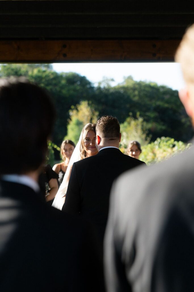 Bride and groom standing at the altar surrounded by family and friends during their outdoor ceremony at 7 Vines.
