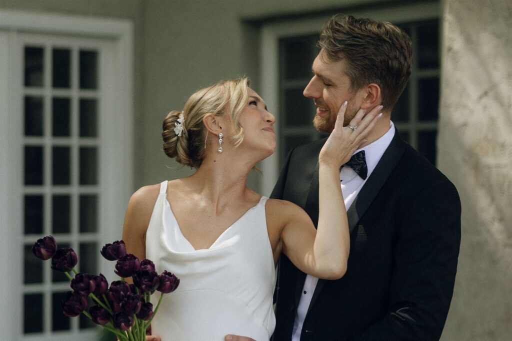 Bride and groom standing close together in open shade, exchanging a quiet look as soft light wraps evenly around their faces, highlighting emotion and connection through intentional wedding lighting photography.