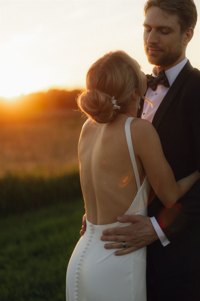 Close-up of bride and groom during golden hour, warm sunlight wrapping around them and highlighting the emotional, intimate feel created by natural wedding venue lighting.